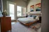 Bright and inviting bedroom featuring a cozy wooden bed with colorful pillows, modern wall art, and large windows for ample natural light.