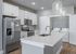 Modern kitchen featuring sleek stainless steel appliances, elegant white cabinetry, and a convenient laundry nook with washer and dryer.