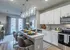 Modern open-concept kitchen and living area with chic pendant lighting, sleek white cabinetry, and stylish bar seating, creating an inviting space for gatherings.