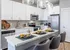 Modern kitchen with sleek white cabinets, stainless steel appliances, and elegant pendant lighting above a breakfast bar with stylish seating.