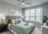 Elegant bedroom with modern decor featuring a gray tufted headboard, stylish throw pillows, and large window for natural light.