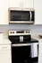 Modern kitchen with sleek stainless steel appliances, featuring a microwave and oven set against stylish white cabinetry.