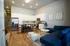 Modern open-concept kitchen and living area with sleek white cabinetry, stainless steel appliances, and stylish hardwood floors.