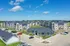 Charming apartment complex with modern architecture, surrounded by lush greenery under a clear blue sky.
