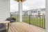 Inviting apartment balcony with cozy wicker chairs overlooking a lush green courtyard and elegant modern apartments.