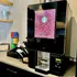 Modern coffee machine with vibrant display, surrounded by colorful tea boxes and elegant decor, creating a cozy cafe vibe.
