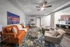 Modern living room with elegant brown leather sofa, artistic rug, and cozy armchairs, seamlessly connecting to a stylish kitchen with bar seating.