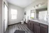 Modern and spacious bathroom featuring a granite countertop, elegant lighting, and sleek flooring, exuding comfort and style.