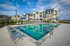 Luxurious apartment complex featuring a pristine outdoor pool, surrounded by comfortable lounge chairs and modern buildings, set against a beautifully sunny sky.