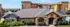 Charming residential complex with stone accents, lush landscaping, and inviting pool area under a clear blue sky.