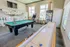 Chic entertainment room with a stylish pool table, vibrant arcade game, and modern vending machine, perfect for leisure and relaxation.