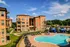 Elegant apartment building with a charming landscaped courtyard, surrounded by lush greenery, featuring a sparkling pool and luxurious shaded cabanas for ultimate relaxation.