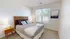 Bright and cozy bedroom with a stylish wooden headboard, soft pillows, and large window offering a serene view.