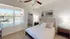Bright and inviting bedroom with plush carpeting, featuring a cozy bed, stylish artwork, ample natural light, and a spacious walk-in closet.