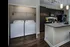Modern apartment kitchen with sleek dark cabinets, a spacious island with seating, large windows for natural light, and an adjacent in-unit laundry space.