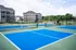 Vibrant outdoor tennis courts set against modern apartment buildings and lush greenery, offering a perfect blend of recreation and residential living.