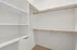 Spacious walk-in closet with built-in shelves and wooden hanging rods, ideal for organized living.