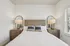 Elegant bedroom featuring a stylish wooden bed frame, pristine white linens, and modern bedside tables with chic lamps.