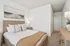 Inviting bedroom featuring a cozy bed with elegant linens, warm wood tones, and soothing artwork, perfect for relaxation.