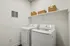 Modern laundry room with sleek washer and dryer, complemented by stylish wicker storage baskets and clean white shelving.