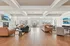 Expansive modern living room with elegant coffered ceiling, cozy stone fireplace, and luxurious leather seating.