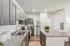 Modern kitchen with sleek gray cabinetry, granite countertops, and stainless steel appliances featuring a spacious island and elegant decor.