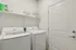 Modern laundry room equipped with high-efficiency washer and dryer, accentuated by sleek white shelving and ample storage space.