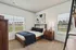 Bright and inviting bedroom with modern decor, featuring a cozy bed, elegant wooden furniture, and large windows offering plenty of natural light.