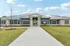 Inviting leasing office with modern architecture, stone facade, and lush grounds under a bright sky.