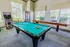 Chic entertainment room with a stylish pool table, vibrant arcade game, and modern vending machine, perfect for leisure and relaxation.