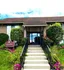 Charming clubhouse entrance with vibrant landscaping and inviting steps, ideal for community gatherings.
