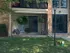 Charming apartment exterior with a cozy patio, hanging plants, and lush greenery, perfect for relaxation.