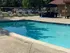 Inviting outdoor pool area with sun loungers and lush greenery, perfect for relaxation under the blue sky.