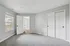 Bright and airy bedroom with plush carpeting, large window for natural light, and sleek sliding closet doors.