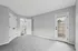 Bright and spacious room with plush gray carpeting, modern white doors, and access to a private outdoor space.