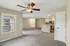 Inviting open-concept living space with plush carpet, modern ceiling fan, and a sleek kitchen with granite countertops.