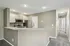Modern open-concept kitchen with sleek stainless steel appliances and a granite countertop, leading to a bright hallway.