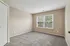 Bright, spacious room with plush carpeting and large windows showcasing greenery, ideal for a serene bedroom setting.