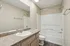 Elegant bathroom featuring a granite countertop, polished sink, and a modern bathtub with a sleek shower design.