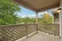 Charming balcony with lattice railing offering serene views of lush green trees under a clear blue sky.