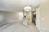 Inviting open-concept living space with plush carpet, modern lighting fixture, and sleek kitchen design, ideal for comfortable living.