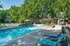 Inviting outdoor pool surrounded by lush greenery and comfortable lounge chairs, perfect for relaxation and leisure.