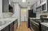Modern kitchen with sleek stainless steel appliances, dark cabinetry, and a convenient laundry area accessible through the doorway.