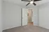 Inviting bedroom with plush carpeting, sleek ceiling fan, and ample closet space, creating a cozy and modern ambiance.
