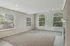 Inviting living room with plush carpeting, abundant natural light, and a cozy fireplace, perfect for relaxation.