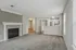 Inviting living space with cozy carpeted area, elegant fireplace, and open-plan kitchen with modern cabinetry and appliances.