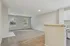 Bright, open living area with plush carpet and natural light pouring through large windows, adjacent to a sleek granite kitchen counter in modern apartment.