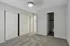 Modern bedroom with plush carpet, built-in closets, and sleek ceiling fan, offering comfort and style.