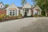 Charming brick and siding exterior with lush landscaping and vibrant flowerbeds, inviting entrance with classic columns.
