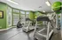 Bright and modern fitness room with treadmills, elliptical, and vibrant green walls, perfect for energizing workouts.